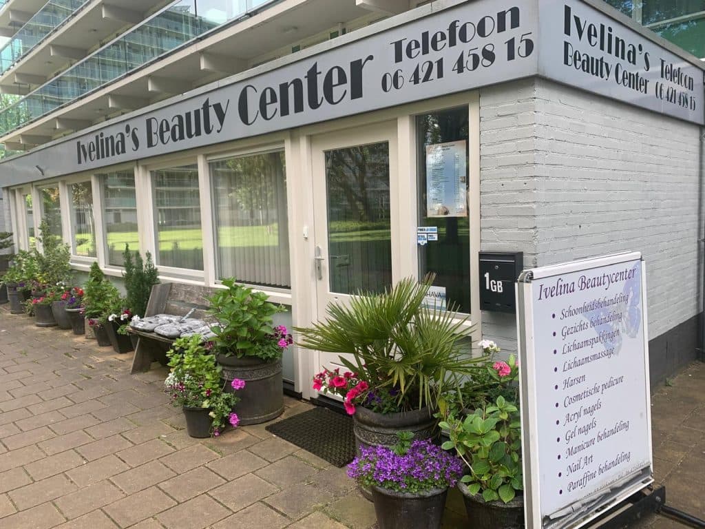 De gevel van de salon aan de Romeflat in Uithoorn, met het grote bord, bloembakken en het stoepbord